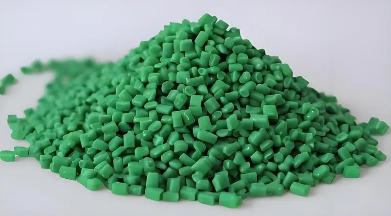 Material de moldeo por inyección verde de policarbonato (PC) en gránulos sobre fondo blanco.