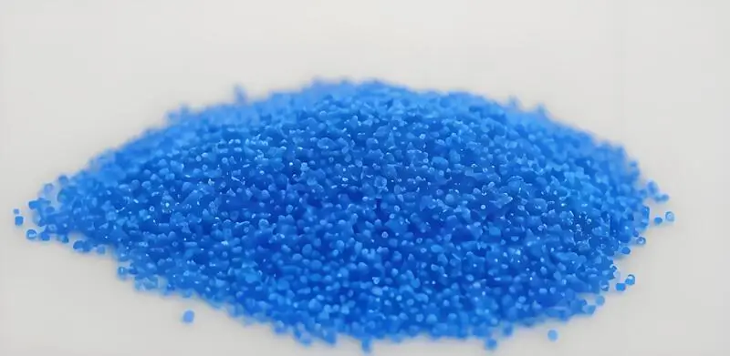 Un montón de pequeños gránulos azules de elastómero termoplástico (TPE) para moldeo por inyección sobre fondo blanco