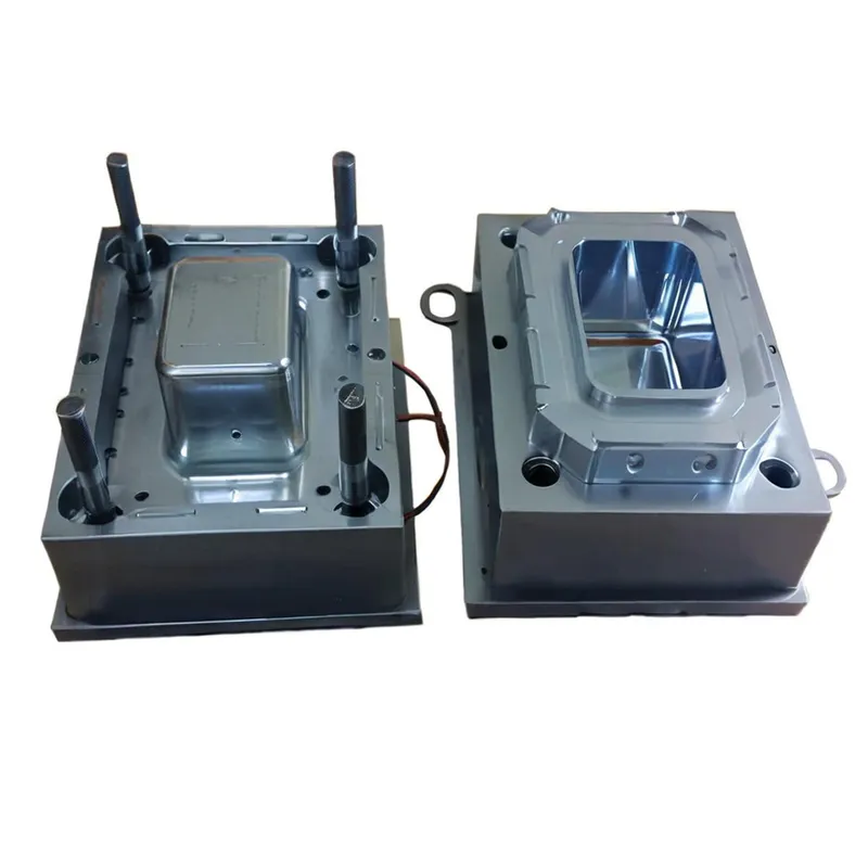 Two metallic die casting molds, one with cylindrical pins and one with a reflective interior surface, used for aluminum biscuit bakeware.