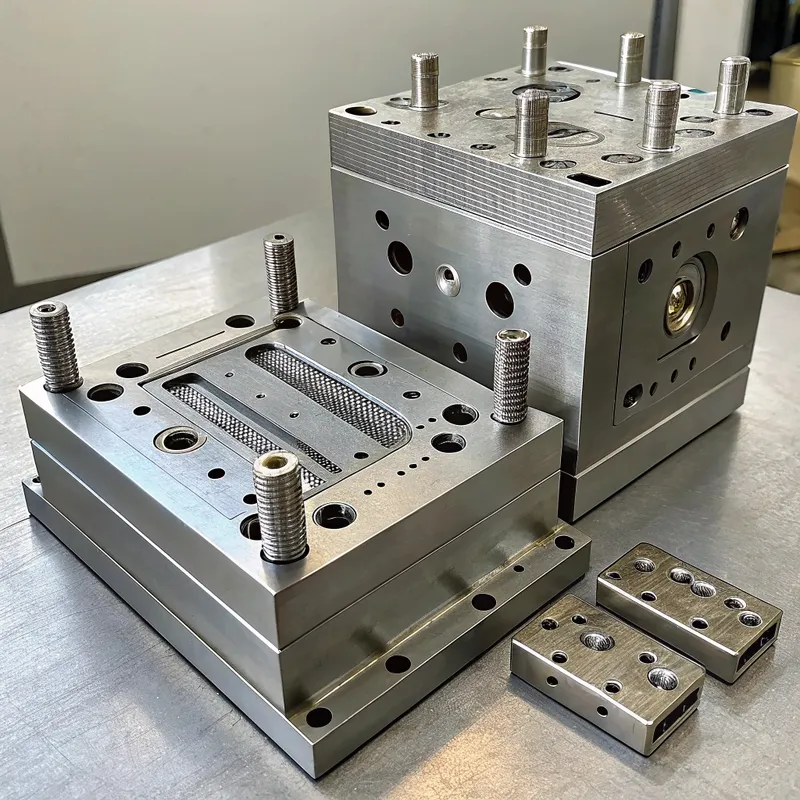 Two large metal molds and smaller components resting on a surface.