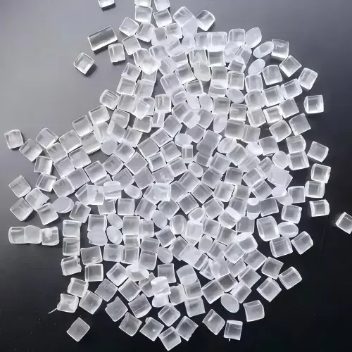 射出成形プロセスに使用される、暗い表面に散らばった透明なプラスチックペレット。