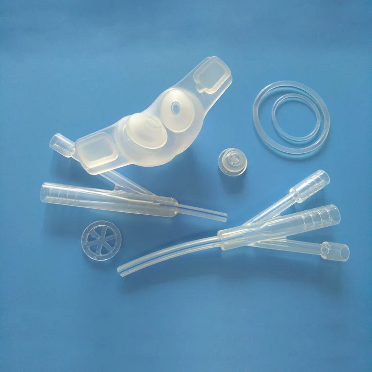 Various transparent silicone injection molded medical components on a blue background.