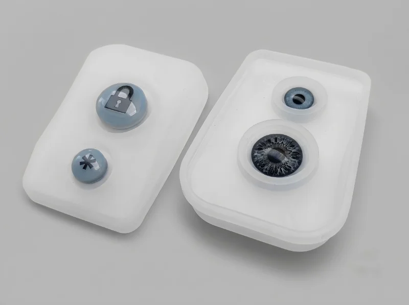 Two plastic injection molded components with intricate designs, featuring a lock and star symbol on the left and an eye-inspired design on the right.